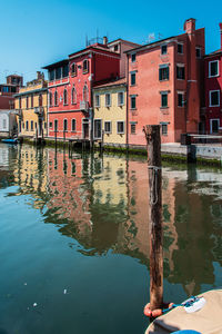Canal by buildings against blue sky