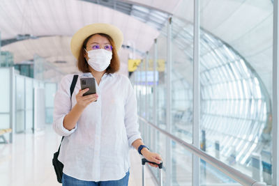 Full length portrait of woman photographing through smart phone