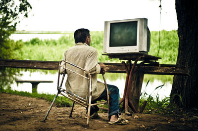 Rear view of man sitting on bench