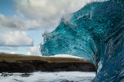 Wave splashing in sea against sky