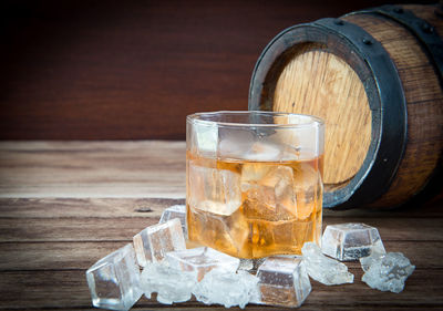 Close-up of ice cubes and whiskey in glass on table