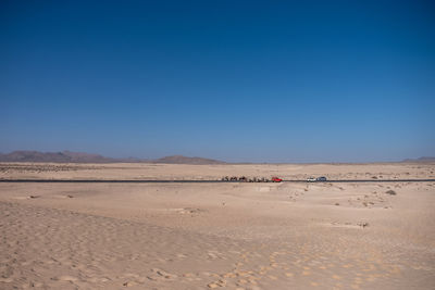 Scenic view of desert against clear blue sky