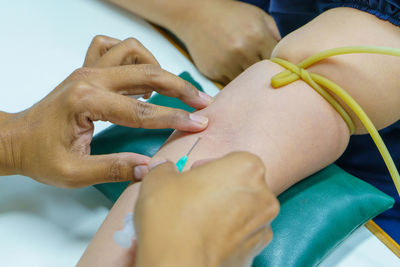 Cropped hands of doctor injecting patient at hospital