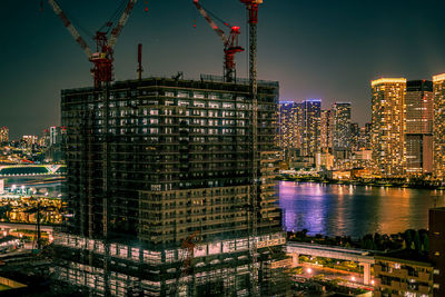 Illuminated modern building in city against sky at night