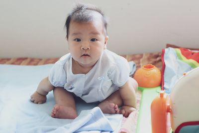 Portrait of cute baby girl on bed at home