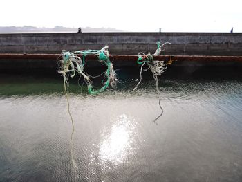 Close-up of fishing net on lake against sky