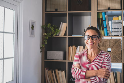 Portrait of smiling woman against book shelf