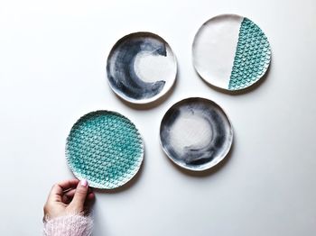 Cropped hand of woman holding plate over white background