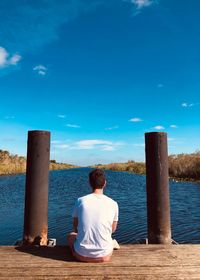Rear view of man sitting against blue sky
