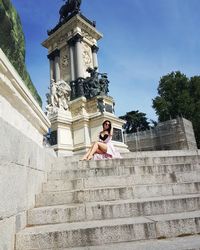 Low angle view of woman by statue against sky