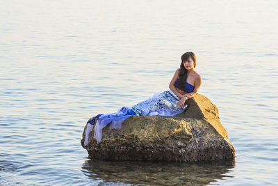 Portrait of young woman sitting on rock