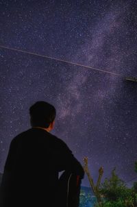 Rear view of man standing against star field at night