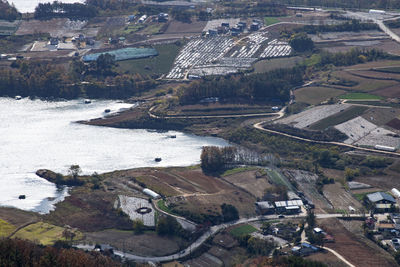 High angle view of lake by buildings in rural field