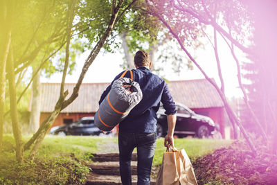 Rear view of man carrying luggage on steps at back yard