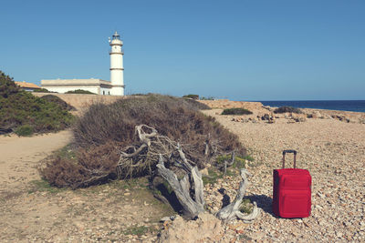 Lighthouse on beach by sea against clear sky