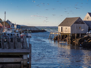 Stilt house by sea against sky