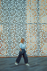 Full length portrait of woman standing against wall