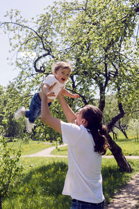 Father throws his son in the flowering garden in the spring