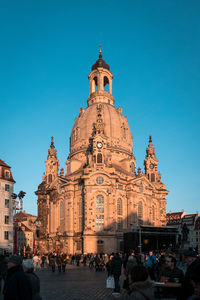 People at cathedral against clear blue sky