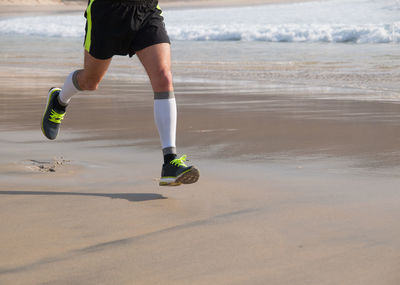 Low section of man running at beach