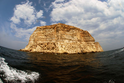 Rock formation in sea against sky