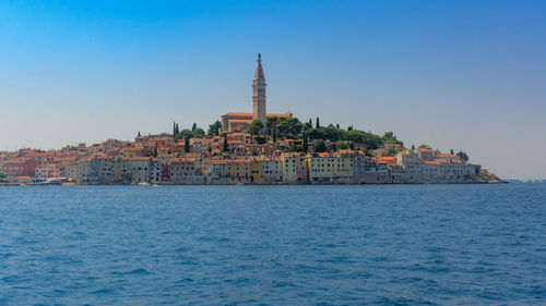View of buildings by sea against sky in city
