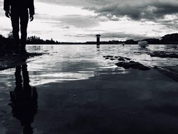 Low section of man on lake against sky