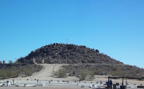 Tourists on mountain against clear blue sky