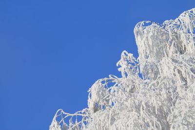 Low angle view of frozen mountain against clear blue sky