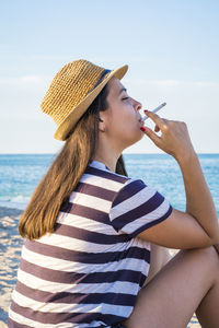 Young woman smoking cigarette at beach