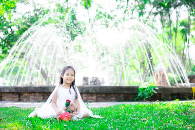 Woman sitting on grass against trees