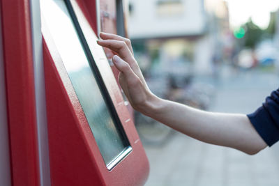 Cropped hand using ticket machine in city