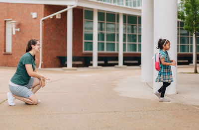 Young millennial mother sending daughter off back to school