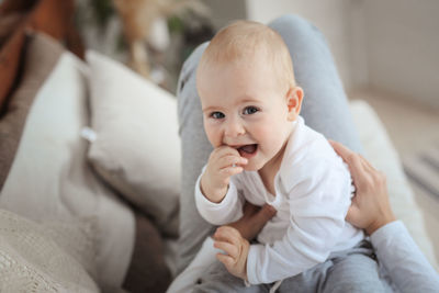 Portrait of cute baby boy sitting on bed at home