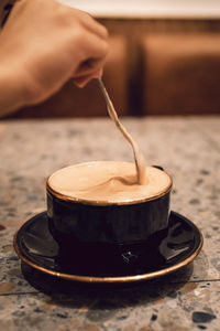 Midsection of person pouring coffee in cup on table