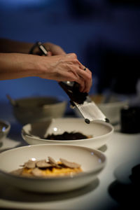 Midsection of person preparing bread in plate on table