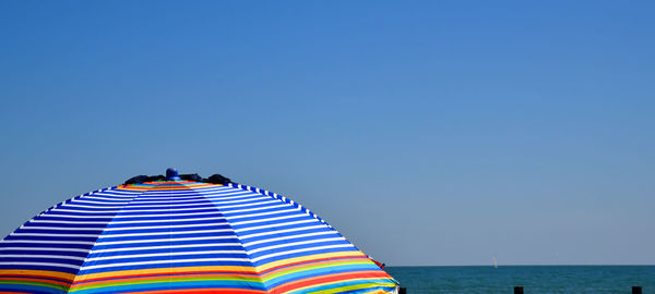 Multi colored umbrellas on beach against clear blue sky