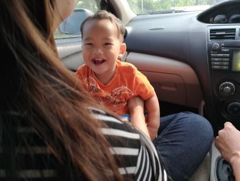 Mother with cheerful son sitting in car