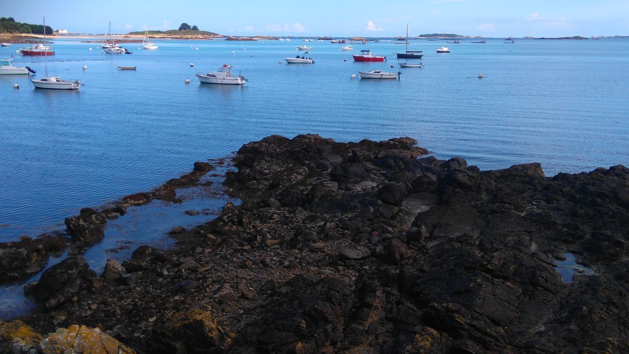 BOATS MOORED ON SEA BY HARBOR AGAINST SKY