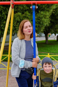 Cute charming boy of five years old,swinging. communication between mother and son on the playground