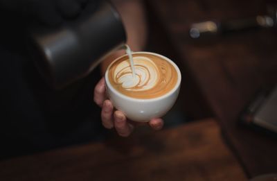 Close-up of hand pouring coffee in cup