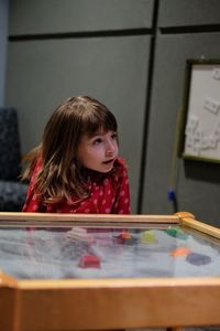 Girl looking away while sitting by table at home