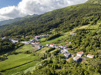 Panoramic view of green landscape and houses against sky