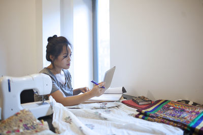 Woman looking at camera while sitting on table at home