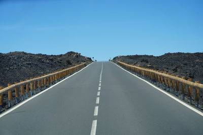 Empty road against clear blue sky