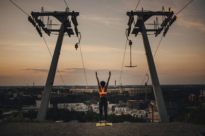 Rear view of sportswoman with hand raised exercising during sunset