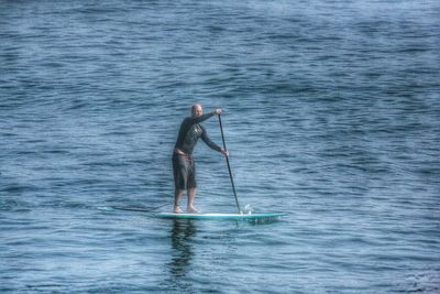 Rear view of man with arms raised on sea