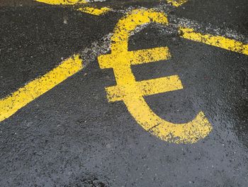 High angle view of yellow euro symbol on wet road