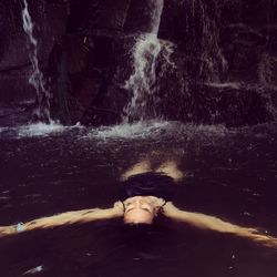 High angle view of woman floating on water at waterfall