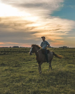 Man ridding a horse at pampa argentino in a sunset